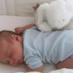 Bébé dort paisiblement en body bleu